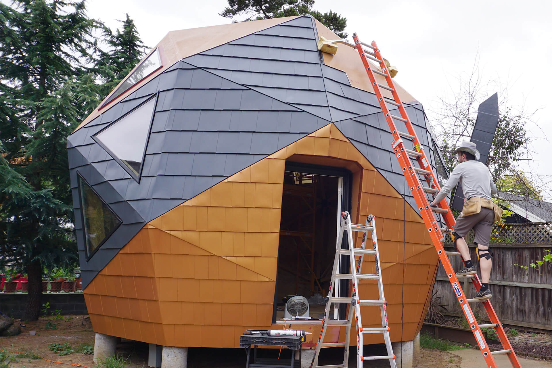 Installing metal roofing shingles on the geodesic dome.