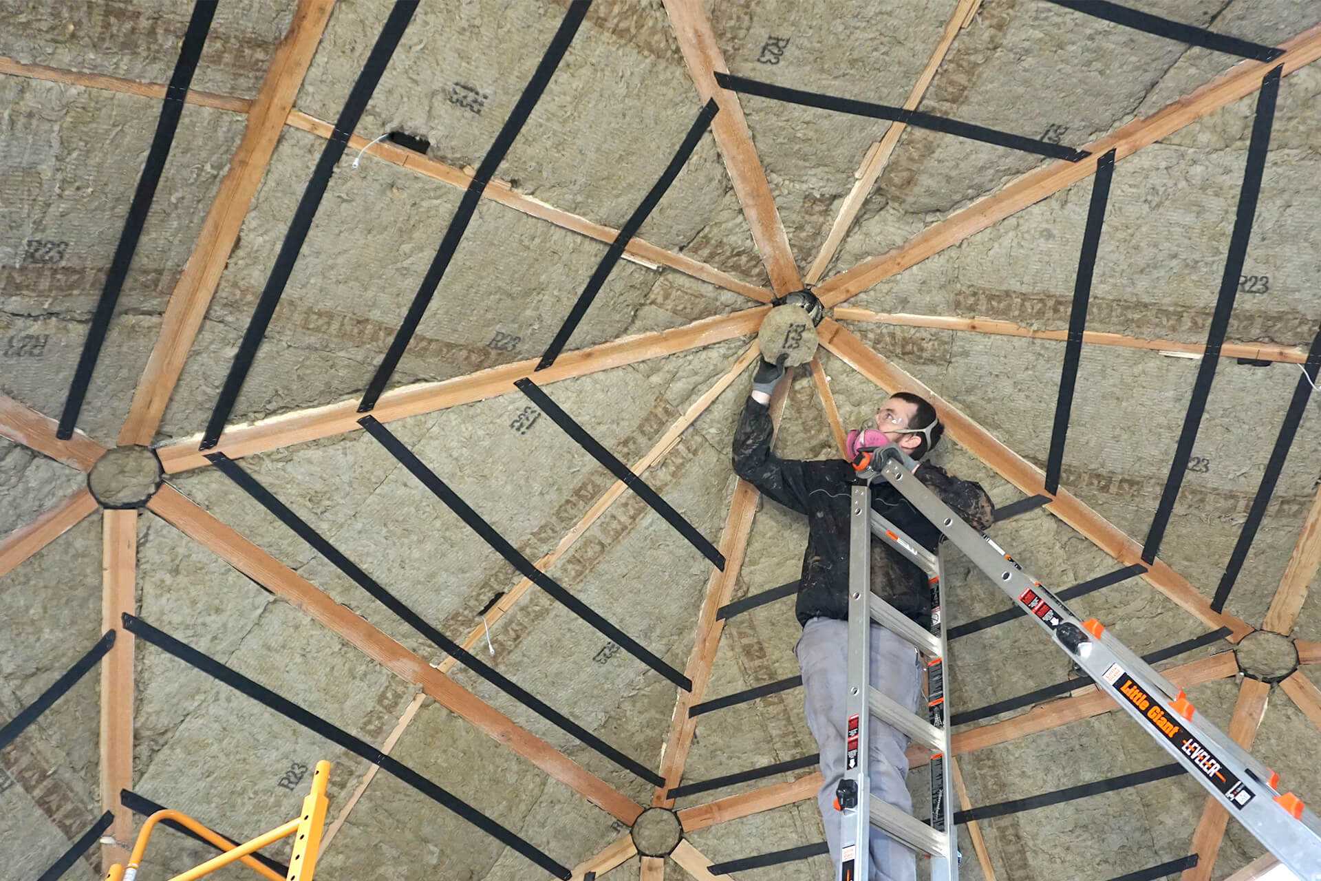Installing the mineral wool insulation into the walls, on top of the spray foam.