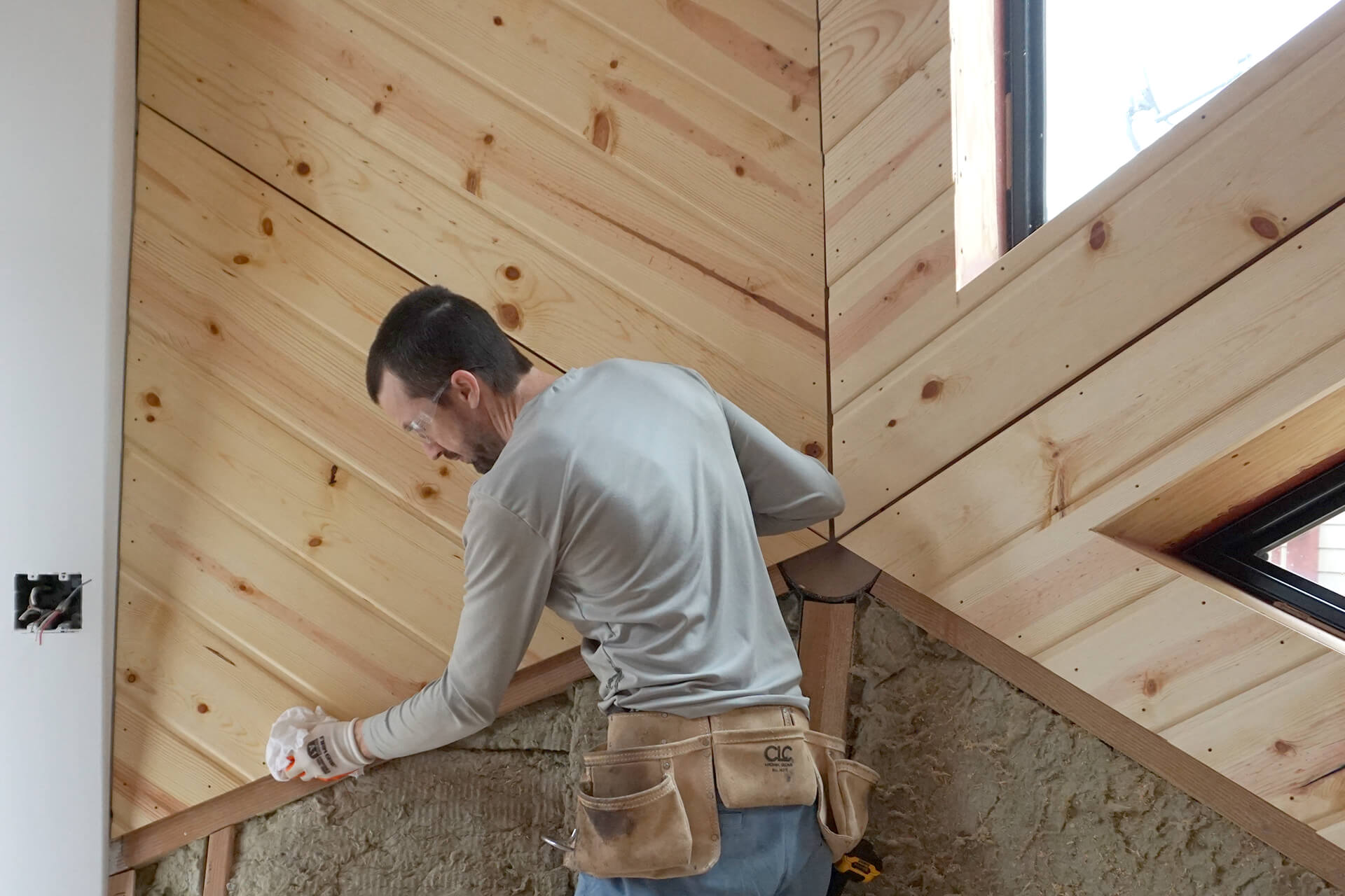 Installing tongue and groove knotty pine as the wall covering.