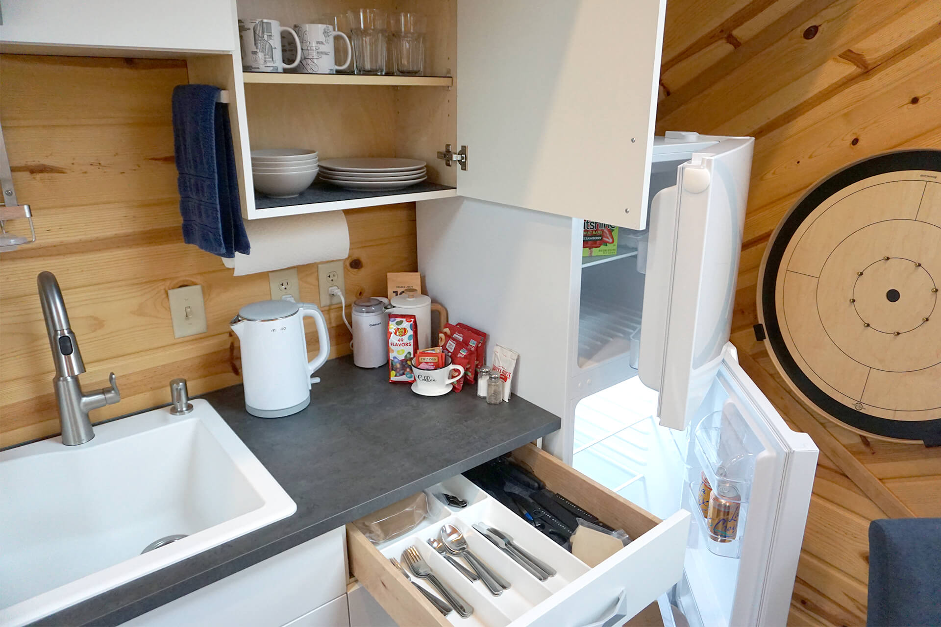 A fully stocked kickenette, with utensils, dishes, and small countertop appliances.