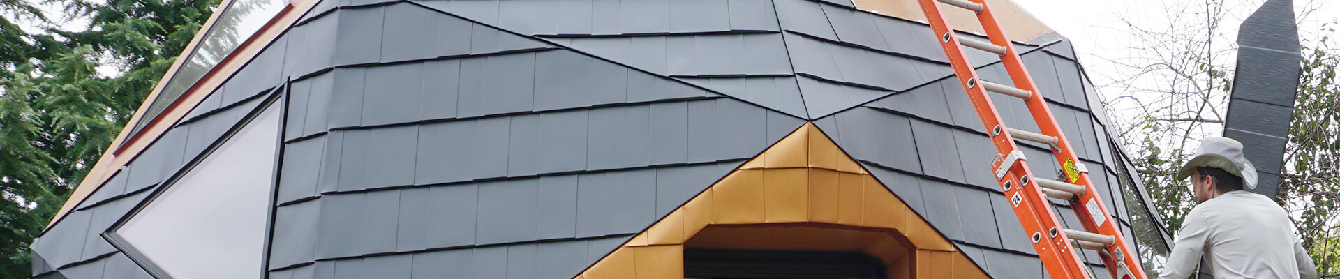 A close-up view of a person installing a metal shingle roof on the Mini Dome.