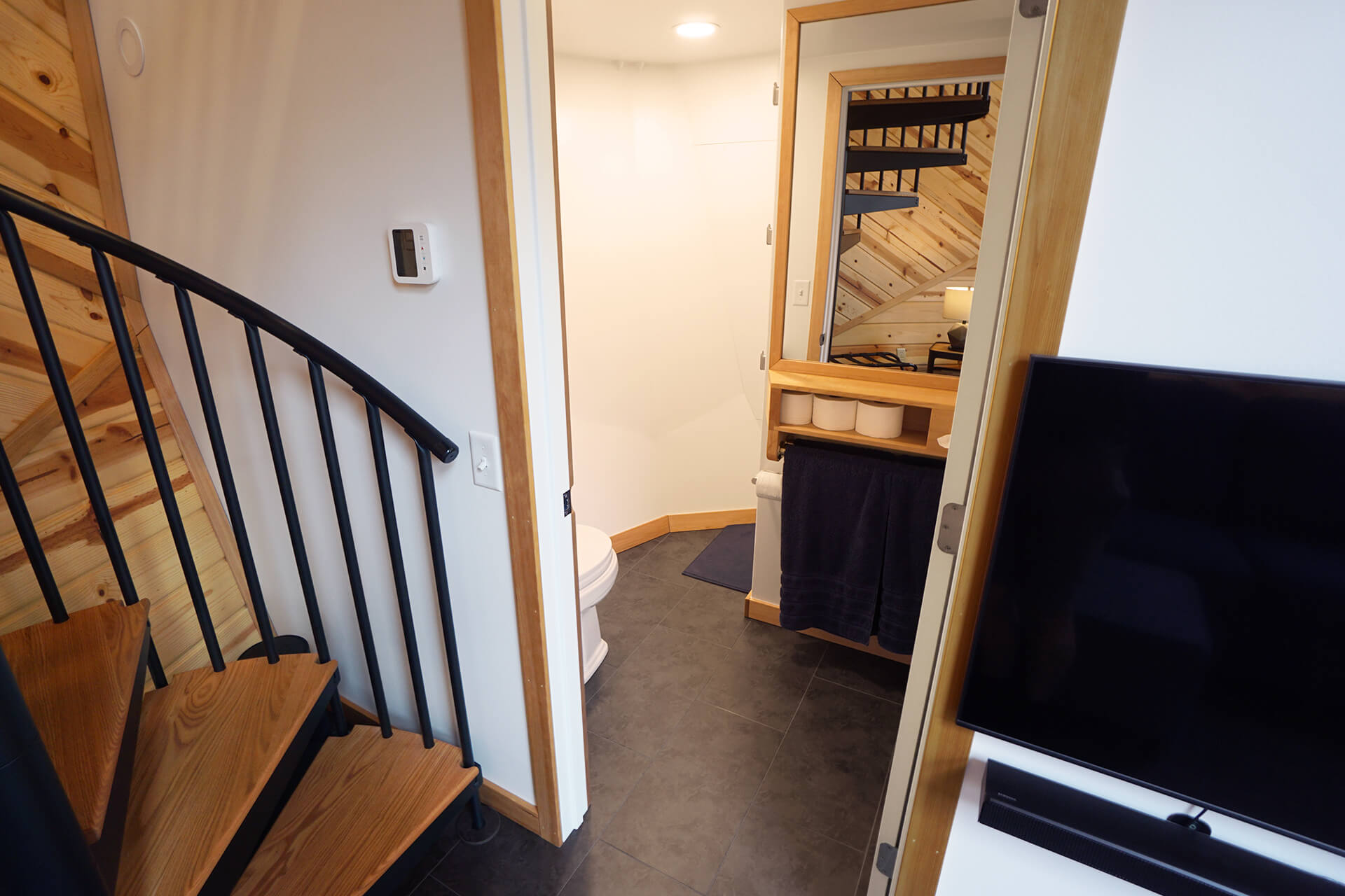 Entering the bathroom door, located next to the spiral staircase and the television.