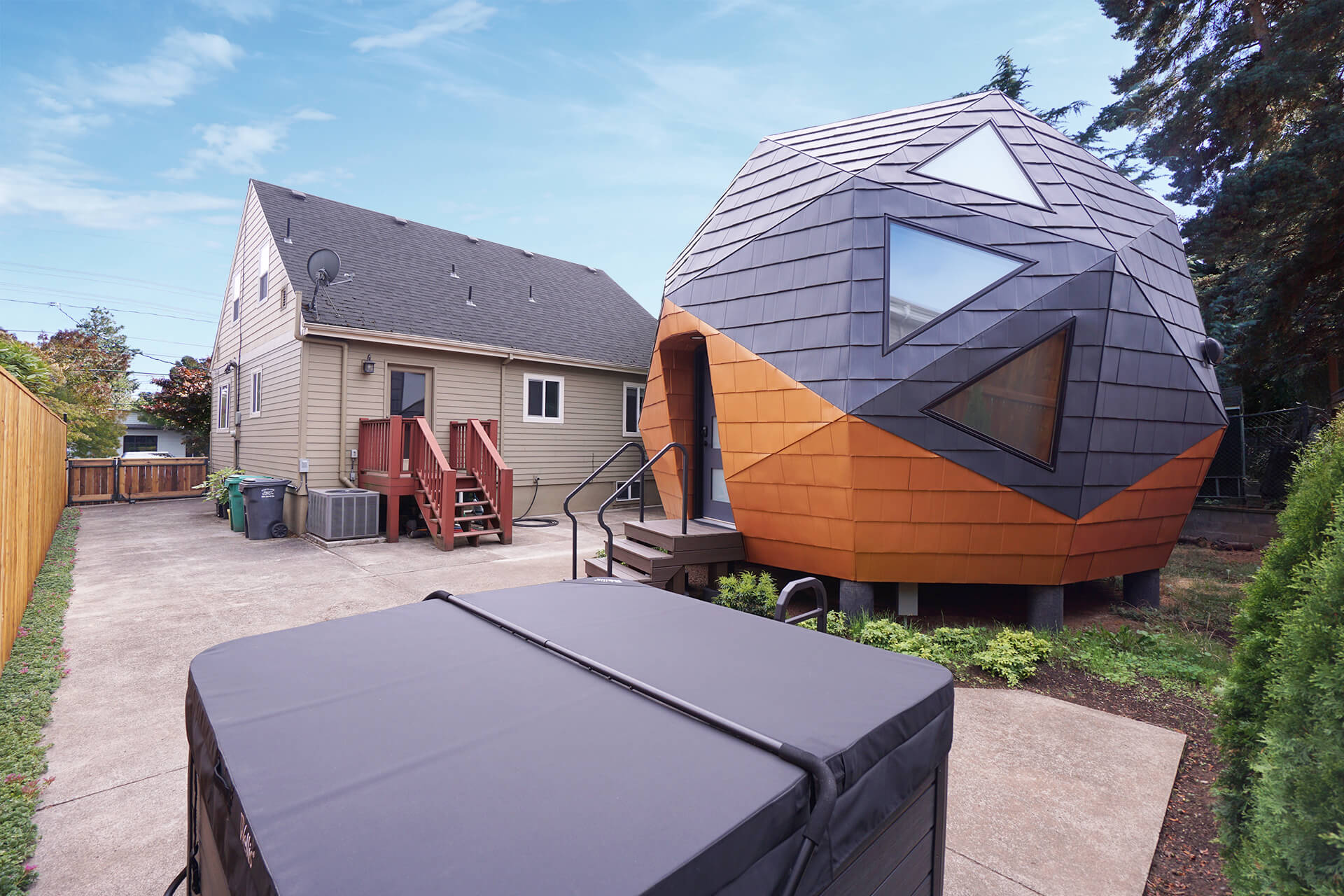 Corner view over the hot tub with the mini geodesic dome home visible behind the primary residence.