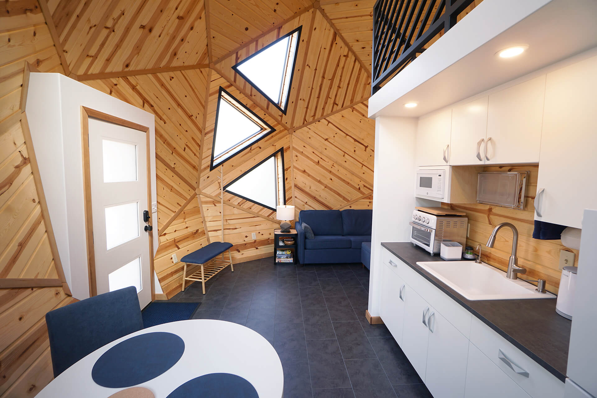 View from the dining room table into the entrance/living room, showcasing three large triangular windows.