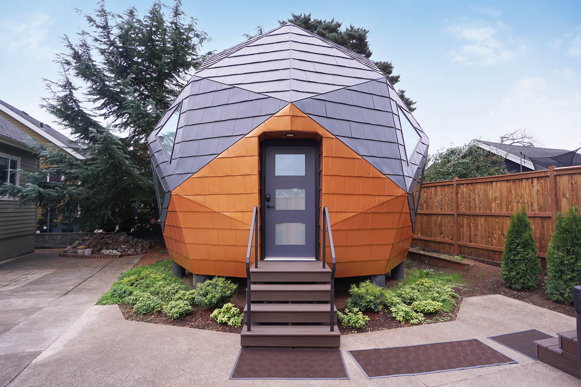 Front view of the mini geodesic dome home, centered on the front door and porch steps.