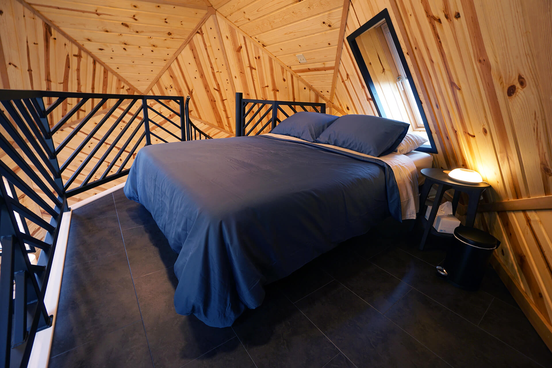 Corner view of the loft, highlighting the standing area around the queen-sized bed.