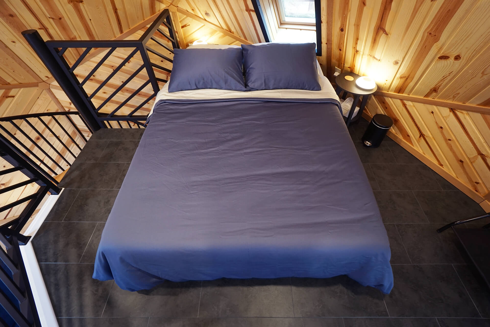 Direct view of the queen-sized bed, featuring an emergency egress window with a darkening shade.