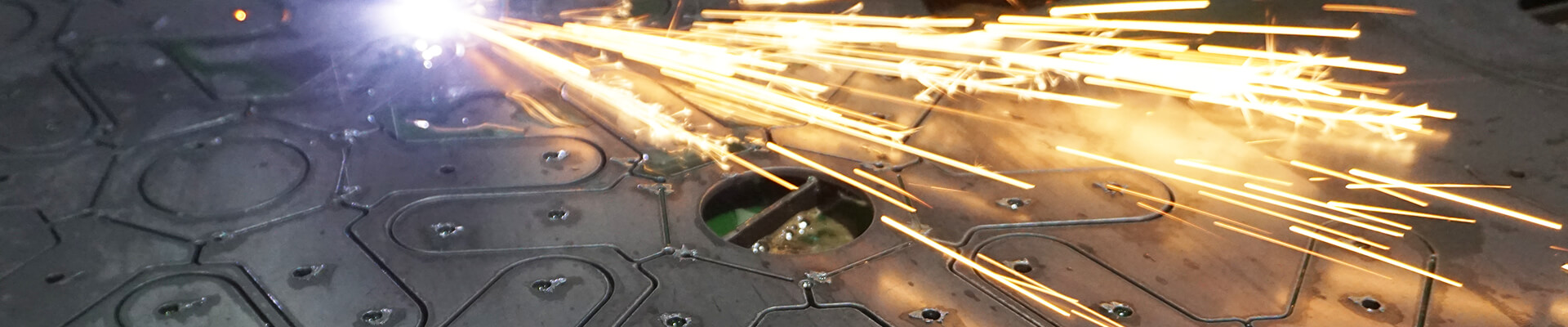 A close-up view of steel being cut with a cnc plasma cutter. Showcasing a unique pattern, and glowing metal sparks. A precision process of cutting metal for the hubs of the geodesic dome.