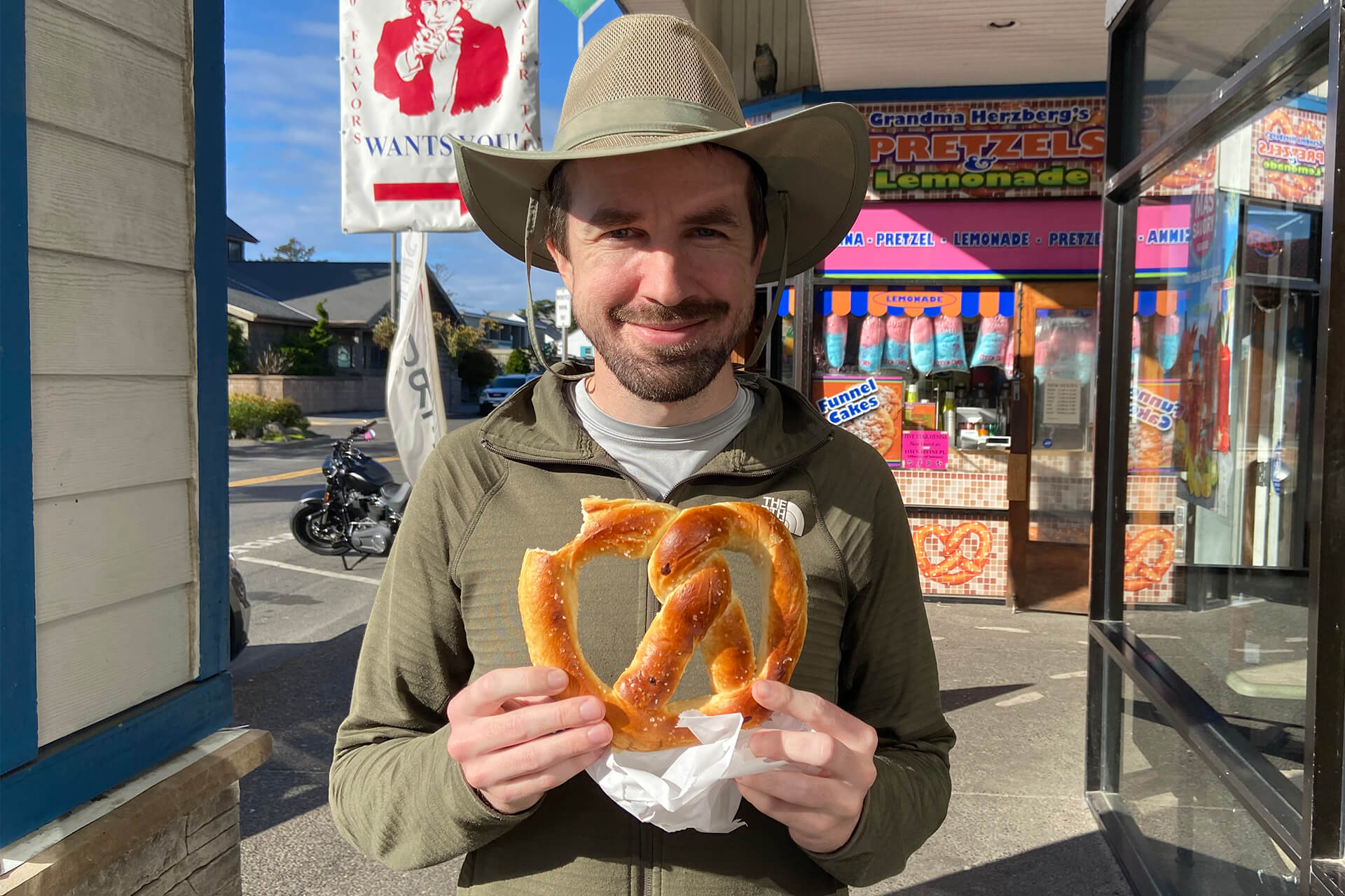 A photo of Joshua Tulberg, the owner and builder, holding a large pretzel.